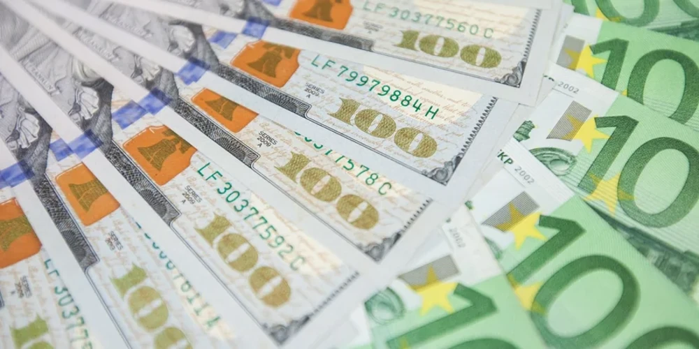 Банкноти долара США та євро на тлі офіційної таблиці курсів Національного банку України